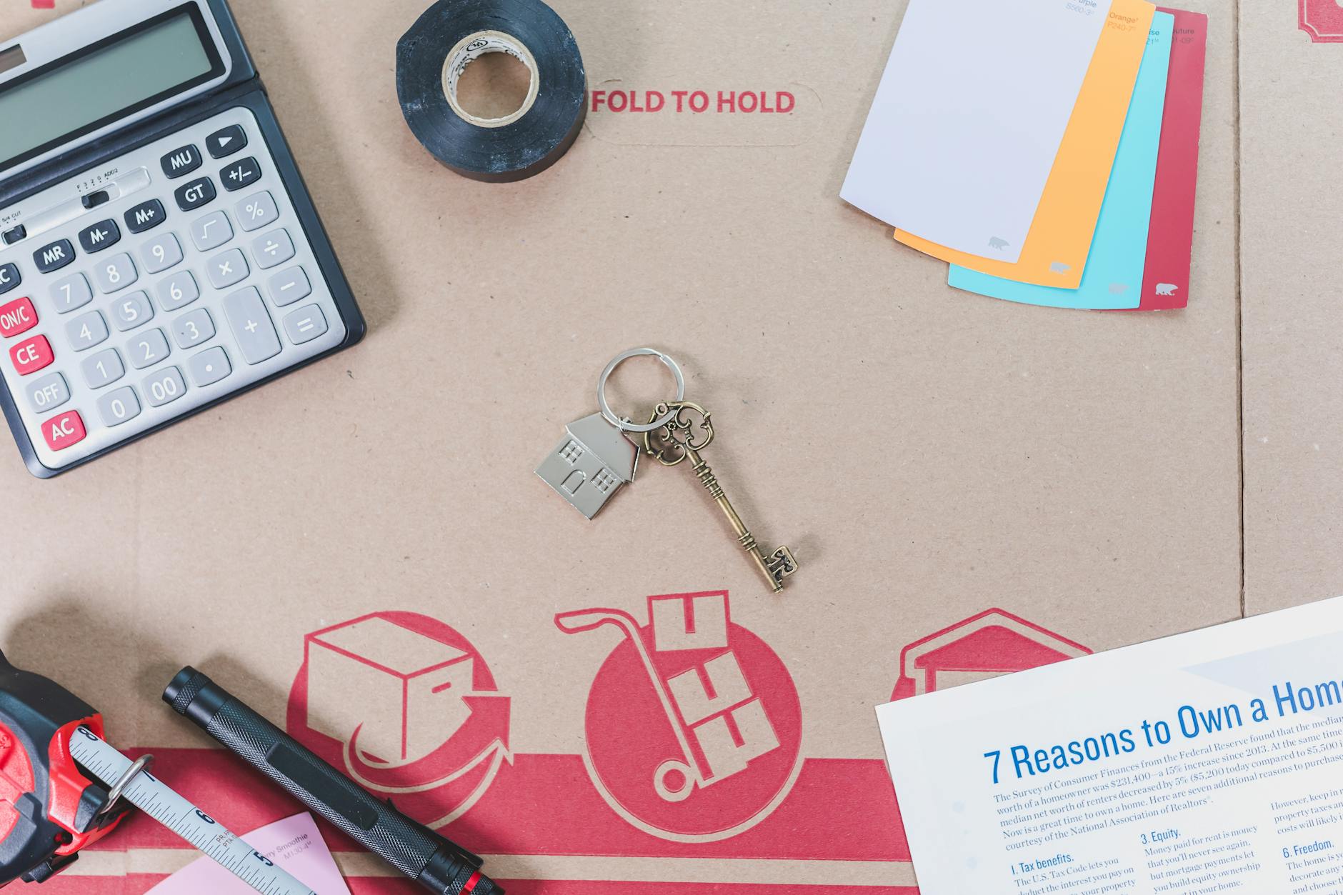 Kalkulator, klucze i próbki kolorów ułożone na stole