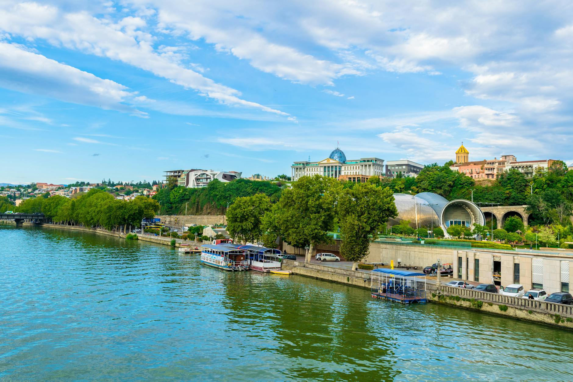 Nadrzeczna panorama Tbilisi z nowoczesną zabudową i statkami wycieczkowymi