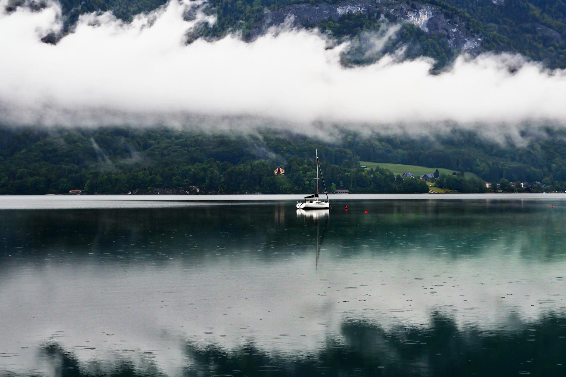 Żaglówka na spokojnym alpejskim jeziorze w Austrii we mgle