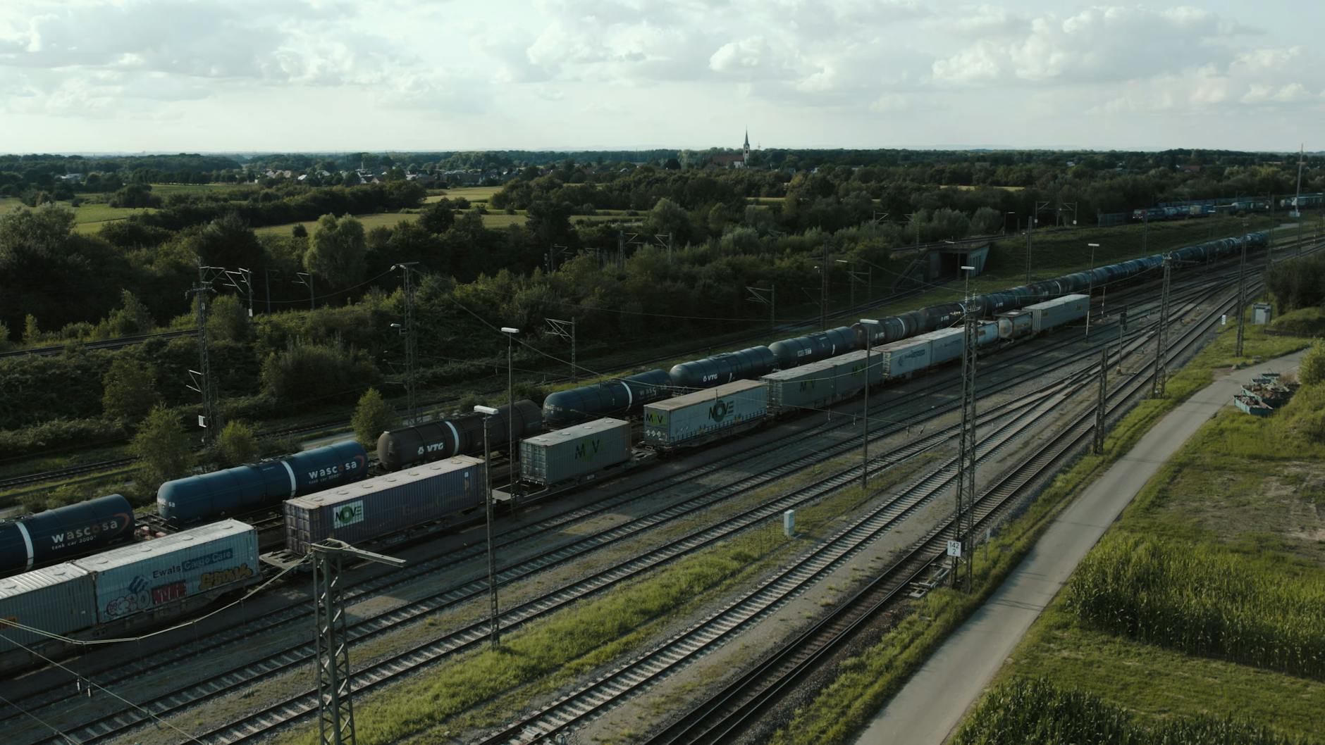 Pociąg towarowy na torach kolejowych w zielonym, wiejskim krajobrazie Pociąg towarowy na torach kolejowych w zielonym, wiejskim krajobrazie