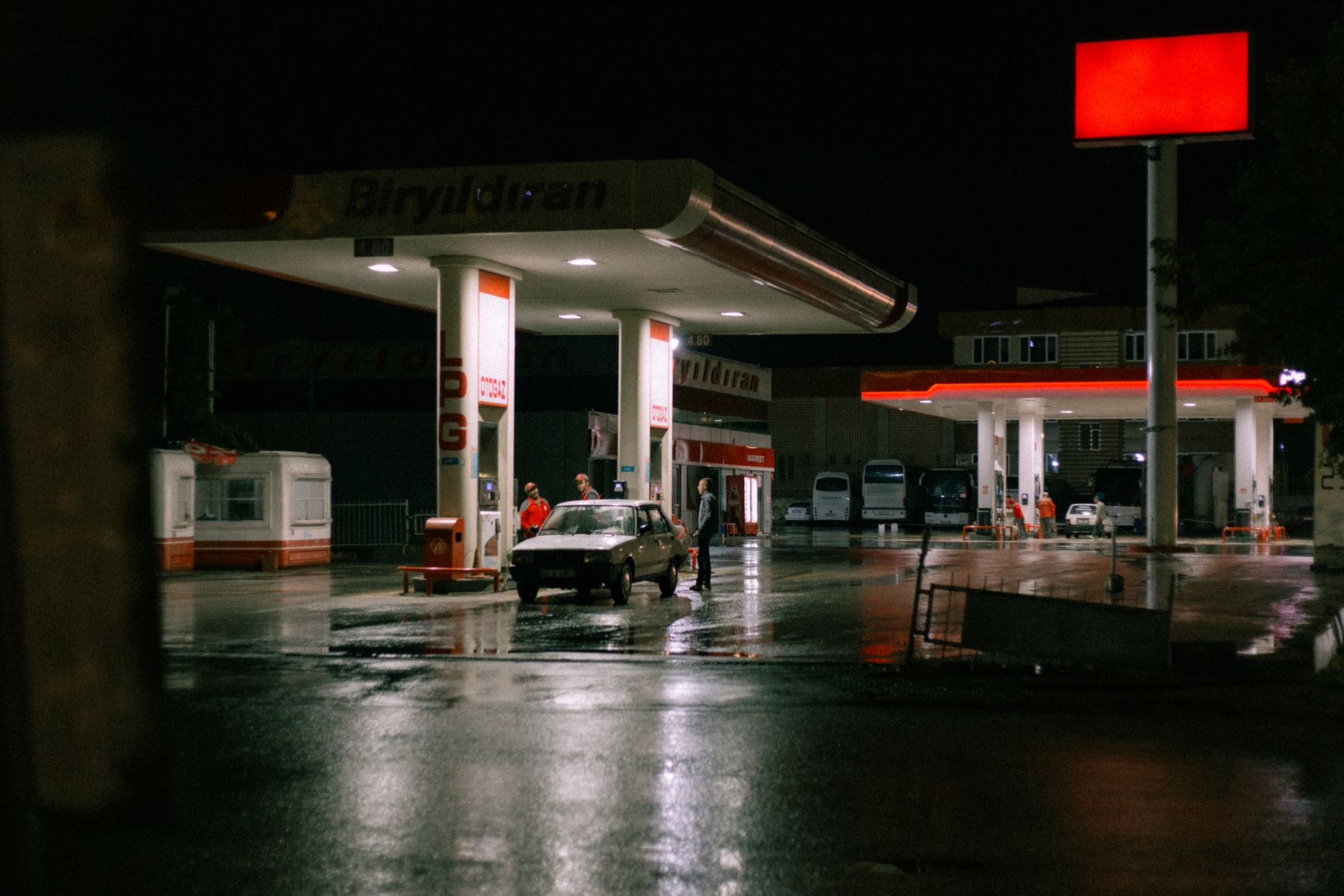 Instalacja LPG w nowoczesnym samochodzie: kiedy się opłaca i na co uważać Samochód i ludzie na oświetlonej stacji paliw nocą