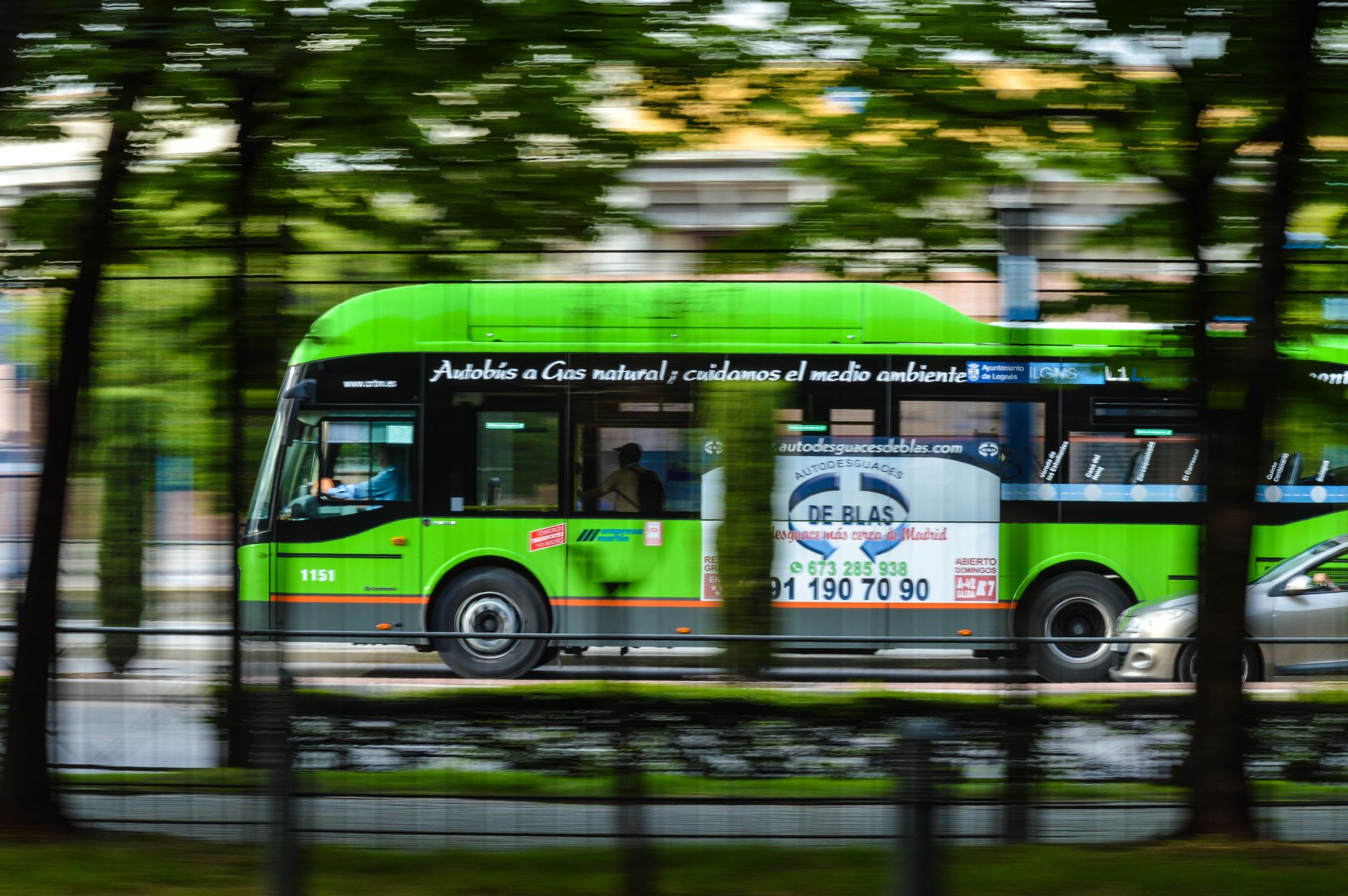 Zielony ekologiczny autobus gazowy jedzie ulicą irlandzkiego miasta Zielony ekologiczny autobus gazowy jedzie ulicą irlandzkiego miasta