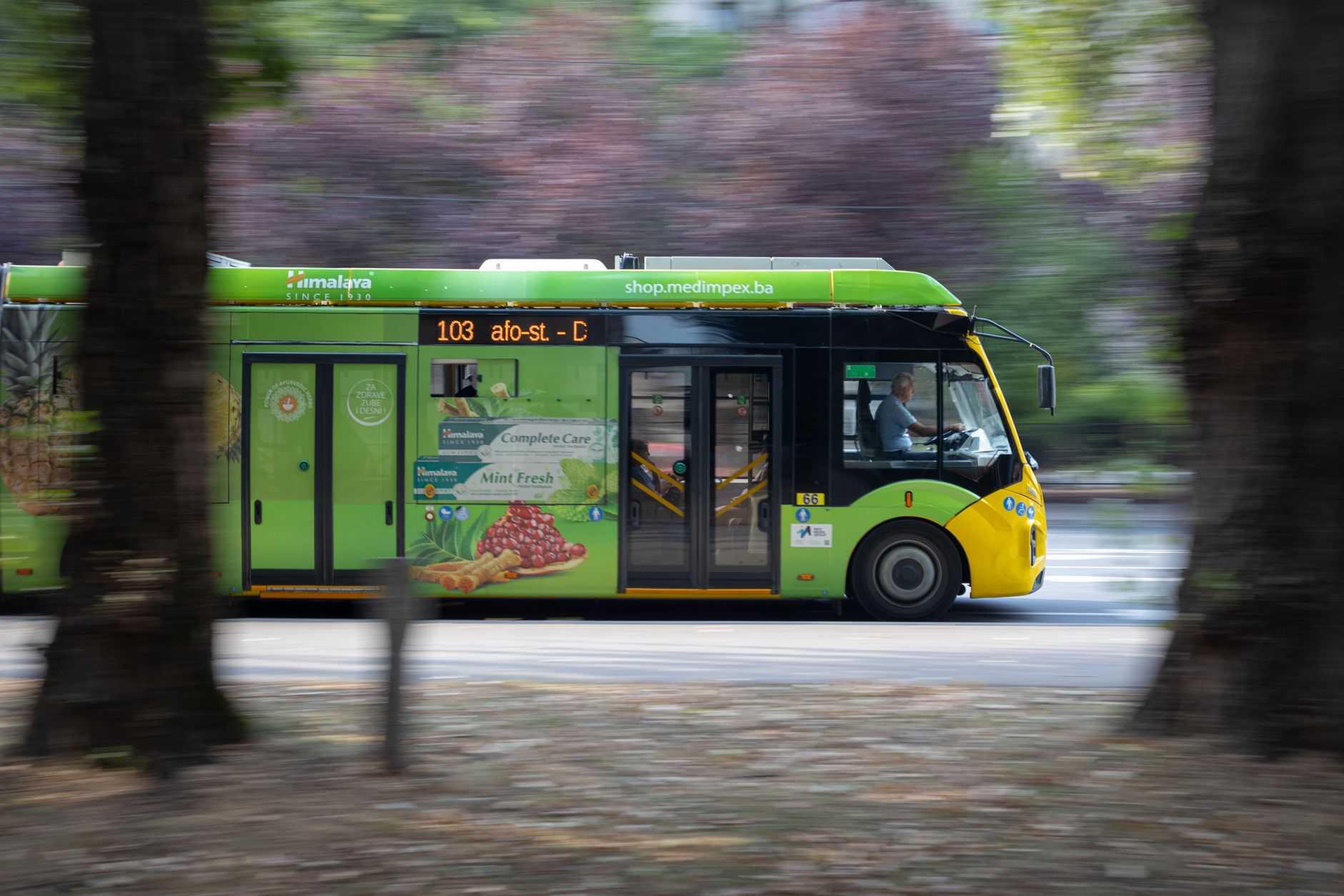 Zielony trolejbus na ulicy miasta wśród górskiego krajobrazu
